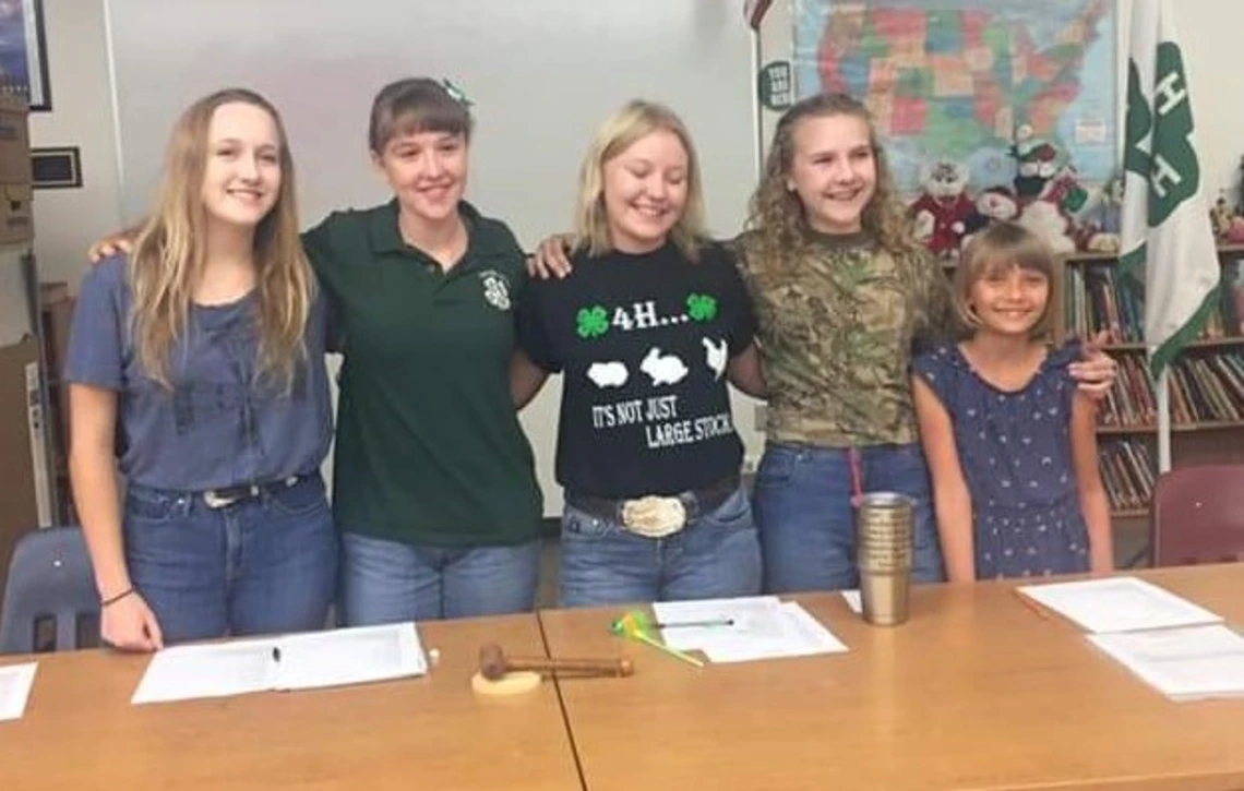 4-H youth smiling behind table