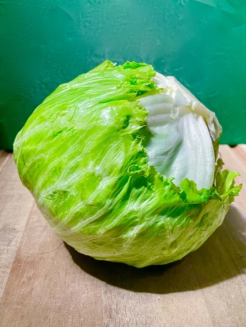 Head lettuce sitting on wooden cutting board