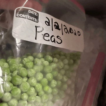 frozen peas in labeled plastic bag in freezer